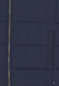 Granatowa kurtka puchowa z mocnym zamkiem, pikowanym wzorem, boczną kieszenią i małą metką z logo. Gładki materiał o lekkiej konstrukcji.