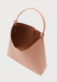 Ροζ δερμάτινη τσάντα με καμπύλο σχέδιο, λεία υφή και μία μόνο λαβή. Το εσωτερικό είναι ανοιχτό χωρίς επιπλέον ορατές τσέπες.
