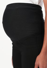 Black maternity leggings with a high elastic waistband, smooth texture, and a close-fitting design, featuring side pocket details.