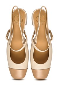 Scarpe slingback in pelle beige con punta aperta, forma arrotondata, suole piatte in tonalità contrastanti tan e logo oro sulla soletta. Dettaglio con fibbia sul cinturino.