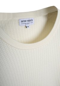 Maglione a costo di colore crema con colletto rotondo a coste e etichetta bianca del marchio "Antony Morato" che indica la taglia media.