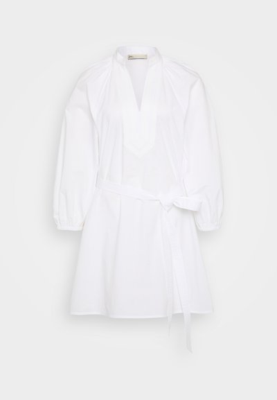 Balta kokvilnas kleita ar izgriezumu, pūkainām piedurknēm un sasietu vidukļa detaļu. Gluda tekstūra ar nedaudz A formas siluetu.