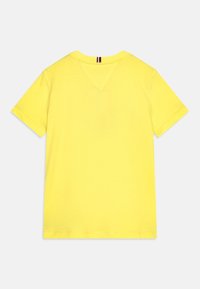 Žluté tričko s krátkým rukávem vyrobené z měkké bavlny. Má V-šv na zadní části krku a rovný lem.
