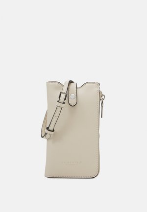 Lille beige lædertaske til at bære over skulderen med justerbar rem, knaplukning og lynlåslomme på siden på ensfarvet baggrund.