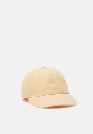 Beige bomulds baseballkasket med buet skygge og topknap, vist mod en ensfarvet lys baggrund.