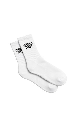 Pair of white crew socks with ribbed cuffs and black text "Vertere Berlin" on the upper side of each sock.
