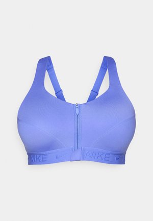 Sujetador deportivo morado con cremallera frontal, con tirantes anchos y una banda elástica con logo texturizado de Nike. Hecho de tela suave y elástica.