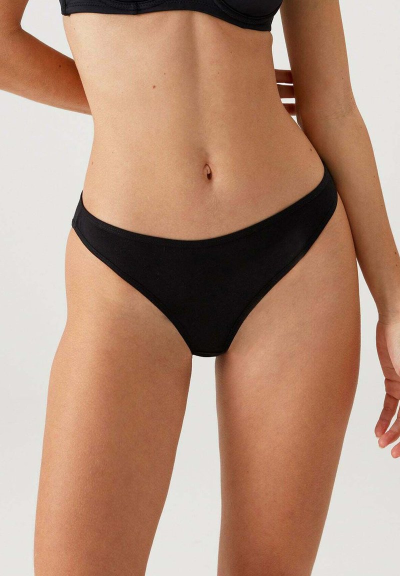 Zwarte bikini slip gemaakt van zacht materiaal met een lage taille, met gladde randen en minimale bedekking. Geen zichtbare patronen of accenten.