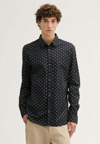 Chemise boutonnée bleu marine avec un petit motif en losanges, à manches longues et col classique. Fabriquée en tissu léger.