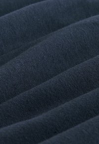 Tkanina w ciemnym granatowym kolorze o fakturze prążkowanego wzoru. Materiał wydaje się miękki i lekko elastyczny, z wyraźnymi poziomymi fałdami.