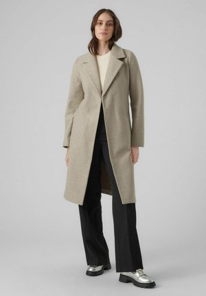 Manteau en laine beige avec un col cranté, des manches longues et une coupe mi-longue. Associé à un pantalon noir et des chaussures argentées pour le contraste.
