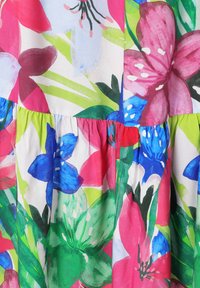 Tissu floral aux couleurs vives : rose, bleu, vert et blanc. Le design comprend de grandes fleurs et des feuilles vertes, avec une texture plissée.