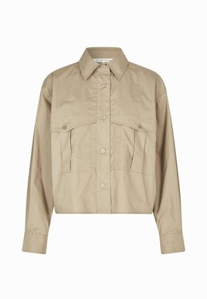 Beige avkortet skjorte laget av bomull, med knappelukking foran, spiss krage og to brystlommer med klaff.