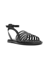 Sandale en cuir noir avec plusieurs lanières horizontales, une fine lanière au niveau de la cheville avec boucle, et une semelle plate. Design minimaliste avec ouvert au niveau des orteils.