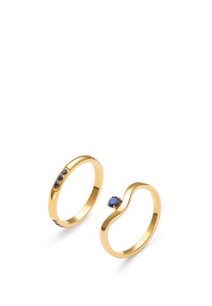 Zwei goldene Ringe, einer mit drei kleinen blauen Steinen entlang des Rings, der andere mit einem einzelnen runden blauen Stein auf einem gebogenen Ring.