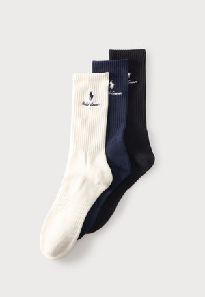 Trois chaussettes montantes côtelées en blanc, marine et noir avec logos brodés de joueur de polo et texte Ralph Lauren sur la zone du mollet.