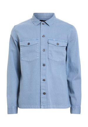 Camicia di denim azzurro chiaro con colletto a punta, maniche lunghe, due tasche sul petto e chiusura frontale con bottoni scuri.