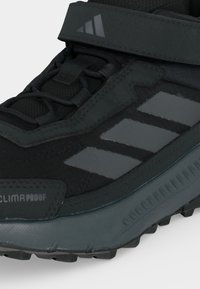 Μαύρο και σκούρο γκρι αθλητικό παπούτσι Adidas Climaproof με καδένα hook-and-loop, συνθετικό επάνω μέρος και τρεις ανακλαστικές ρίγες στο πλάι.