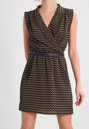 Robe sans manches à col en V avec motif zigzag noir, marron et blanc, cintrée à la taille par une ceinture fine bleu foncé.