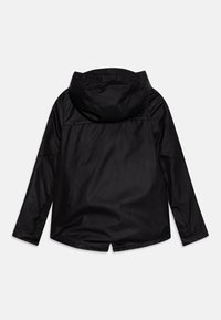 Chaqueta negra impermeable con capucha, que presenta mangas largas y un corte recto. Textura suave, diseño minimalista, sin herrajes ni acentos visibles.