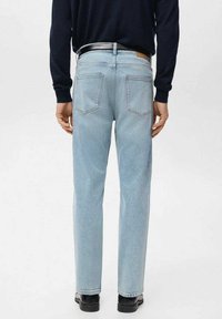 Jeans de mezclilla azul claro con un corte recto, que cuentan con bolsillos traseros y una etiqueta de cuero en la cintura. Textura suave, con los puños doblados en los tobillos.