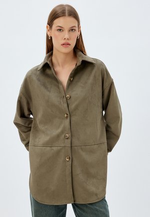 Chemise en daim doux de couleur vert olive, avec un devant à boutons, un col classique et une coupe décontractée ; présente de grands boutons et des poches latérales.