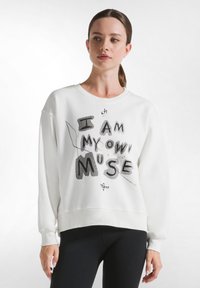 Felpa bianca caratterizzata da un audace testo in nero e grigio che recita "IO SONO LA MIA STESSA MUSE," con una vestibilità comoda e polsini a costine.