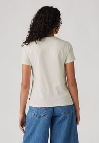 Ljusbeige kortärmad t-shirt i mjukt material, med rund halsringning och en lätt stretch. Matchad med blå vida jeans.