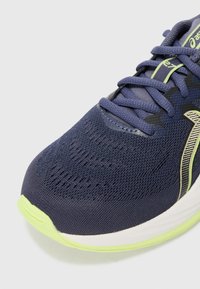 Navy mesh running shoe with lime green accents. Features textured upper, round toe, and flat laces. Lightweight outer sole material.