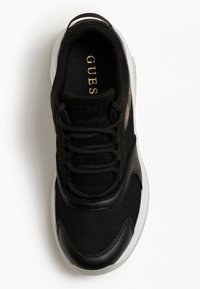 Chaussure de sport noire avec tige en mesh, accents en cuir lisse, semelle intermédiaire blanche et logo "GUESS" en or sur la semelle intérieure. Conception à bout arrondi.
