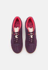 Sneaker in suede viola con dettagli rosa, dotati di una suola texturizzata, lacci bianchi e un rivestimento interno con motivo geometrico.