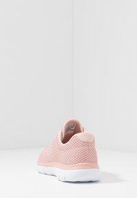 Basket de sport en mesh rose clair avec un col rembourré, un corps texturé et une semelle en caoutchouc blanche. Design élégant avec une marque minimale sur le côté.