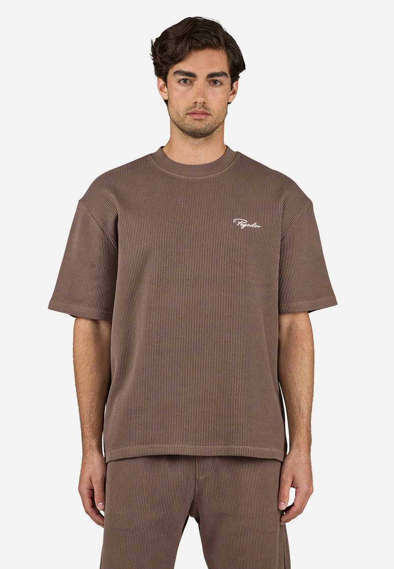 Brun ribbet kortærmet t-shirt med rund hals, der har et hvidt logo på venstre side. Materialet ser ud til at være struktureret og blødt.