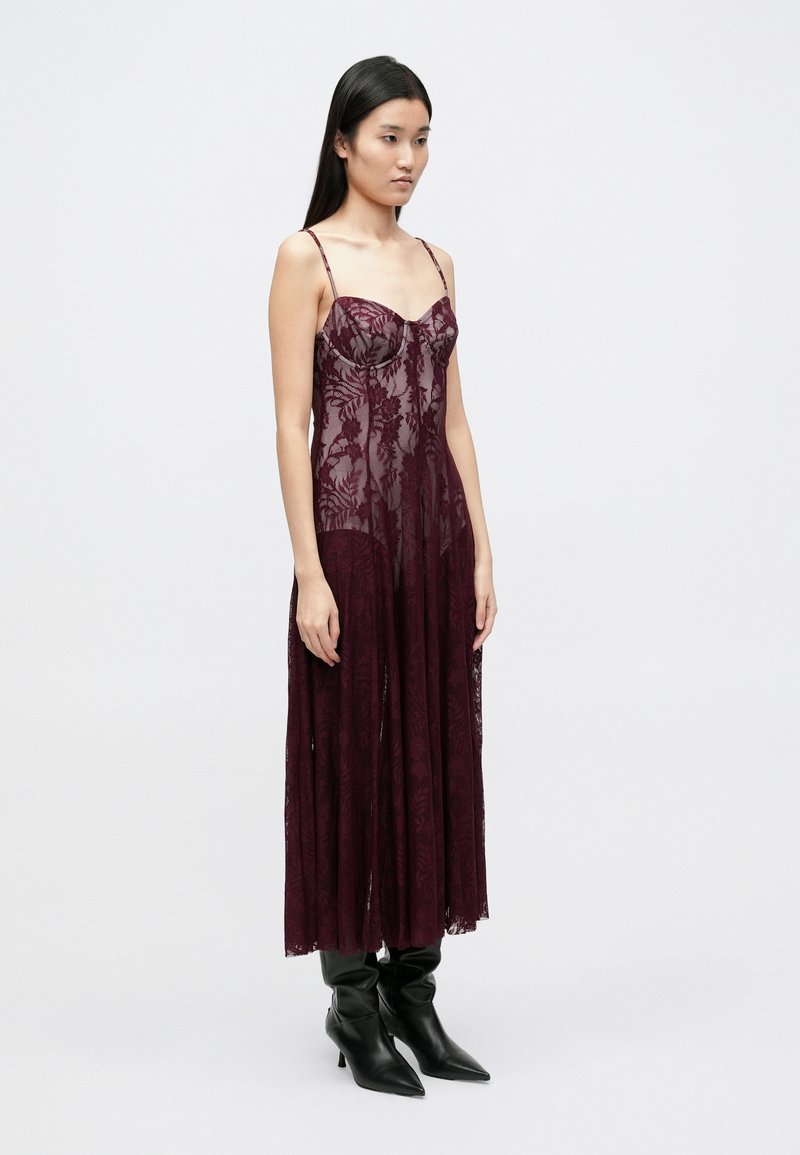 Robe en dentelle bordeaux à fines bretelles, ornée de motifs floraux et d'un bas fluide. À assortir avec des bottines noires à bout pointu.
