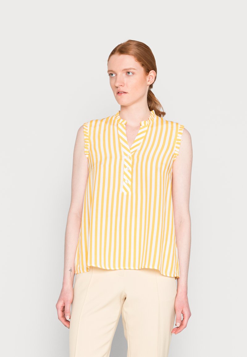 Blusa sem mangas com riscas verticais amarelas e brancas, apresentando um colarinho mandarim e mangas com volantes. Tecido leve com um design fluido.