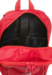 Mochila roja con un compartimento principal con cremallera y bolsillo delantero, que cuenta con un interior negro, correas ajustables y un acabado de tela texturizada.