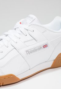 Sneaker in pelle bianca con suola in gomma, presenta il logo Reebok, design con lacci e colletto imbottito per il comfort. Estetica pulita e semplice.