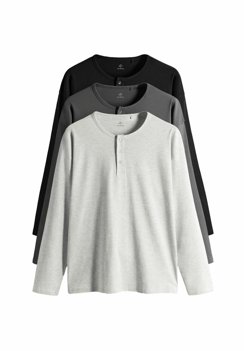 Tres camisetas henley de manga larga en gris, gris oscuro y negro. Hechas de algodón suave, con tapeta de botones y cuello redondo.