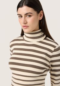 Pulover cu guler înalt și dungi, având dungi alternate de culoare maro și crem, realizat dintr-un material ribbed, evidențiind un design ajustat și un guler înalt.