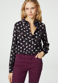 Zwarte overhemd met knopen, versierd met witte en paarse bloemmotieven, met een kraag en lange mouwen, gecombineerd met diep paarse broek.