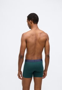 Ανδρικά μποξεράκια σε σκούρο πράσινο βαμβάκι με ναυτικά λάστιχα στη μέση. Διαθέτουν εφαρμοστή σχεδίαση και μήκος μέχρι το μέσο του μηρού.