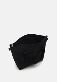 Czarna torba na zakupy z zamkiem, materiałowa, prostokątna, z dwoma uchwytami i zewnętrzną kieszenią. Gładka tekstura, minimalistyczny design.