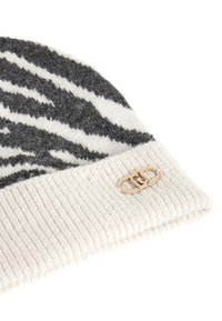 Berretto lavorato a maglia con un motivo a zebra grigio e bianco, bordo a coste piegato e un dettaglio del logo dorato sul lato.
