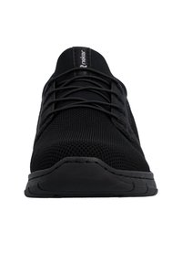 Vue de face d'une chaussure de sport noire avec une texture tricotée, des lacets noirs et une semelle épaisse sur un fond blanc.
