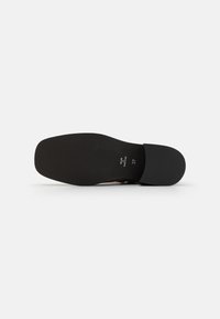 Suela de zapato negra con patrón de agarre texturizado y punta redondeada. Las marcas indican "Hecho en Portugal" y tamaño "37". Acabado suave en la parte superior.