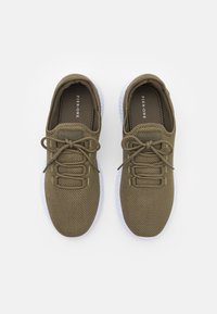 Baskets en maille vert olive avec des bouts ronds, des tiges texturées et des semelles en caoutchouc blanc. Comprend quatre œillets et des lacets assortis.