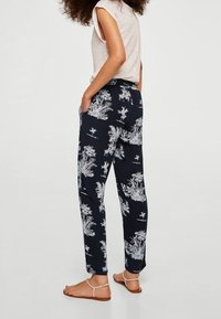 Námořnické kalhoty s bílým tropickým potiskem, volného střihu, se bočními kapsami a měkkou, lehkou tkaninou. Klasický ležérní design.