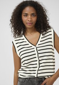 Striped sleeveless knit top in cream and black with a V-neck and button closure. Textured fabric with ribbed edges.
