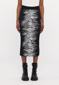 Črna midi krila z belim vzorcem zebra in blagovno znamko. Material je gladek z tesnim pasom. V kombinaciji z črnimi gležnjarji.