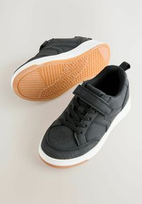 Czarne sneakersy z gładkiego materiału, z wiązanym zapięciem, paskiem na rzep, białą podeszwą środkową oraz teksturowaną gumową podeszwą.
